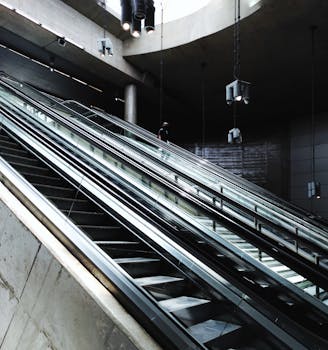 Unrecognizable passenger going down on moving staircase inside of underground railway station in daylight